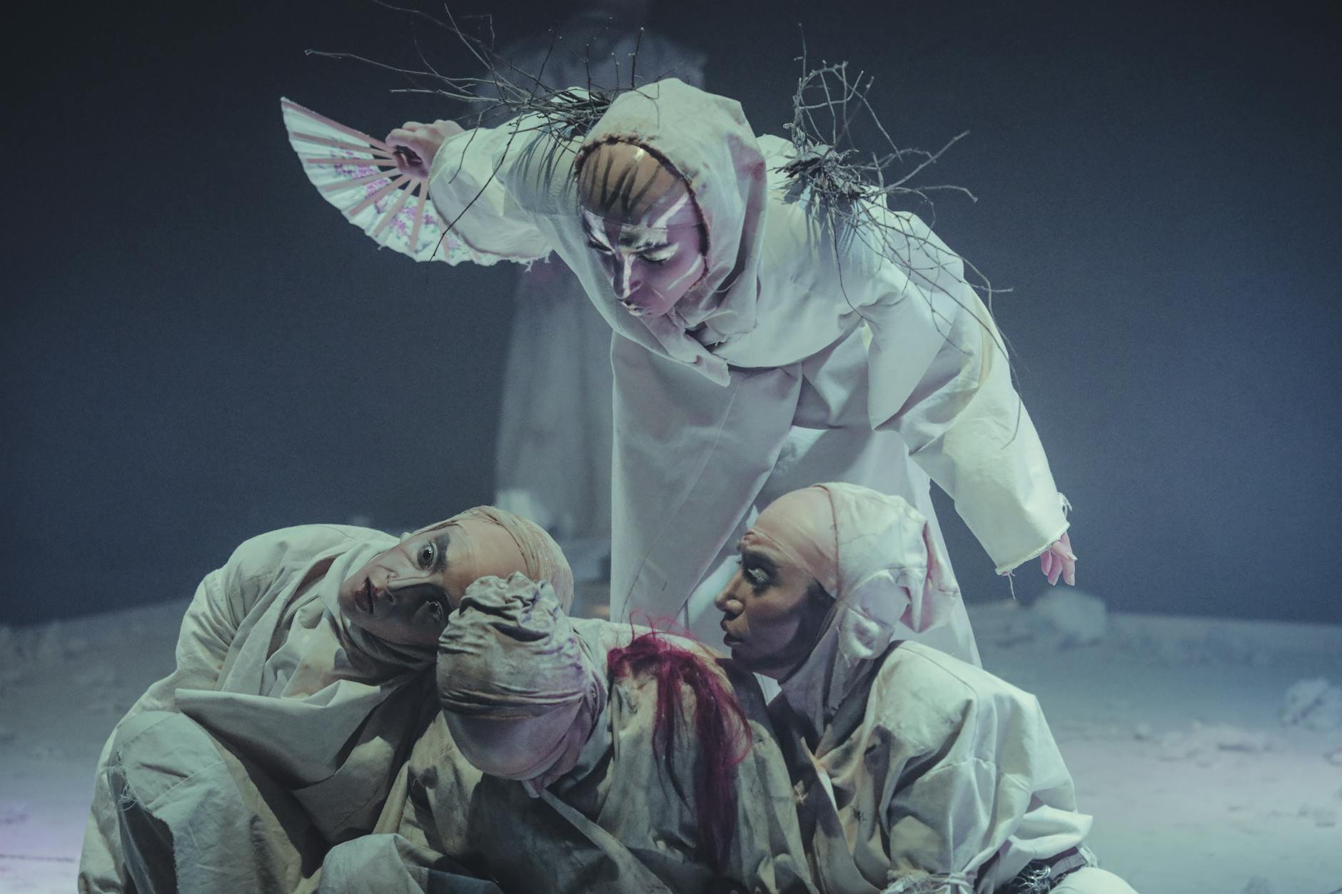 Performers in elaborate costumes on stage during a theatrical play, creating an artistic and dramatic scene.