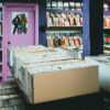 A colorful comic book store with organized shelves and boxes of comics for sale.