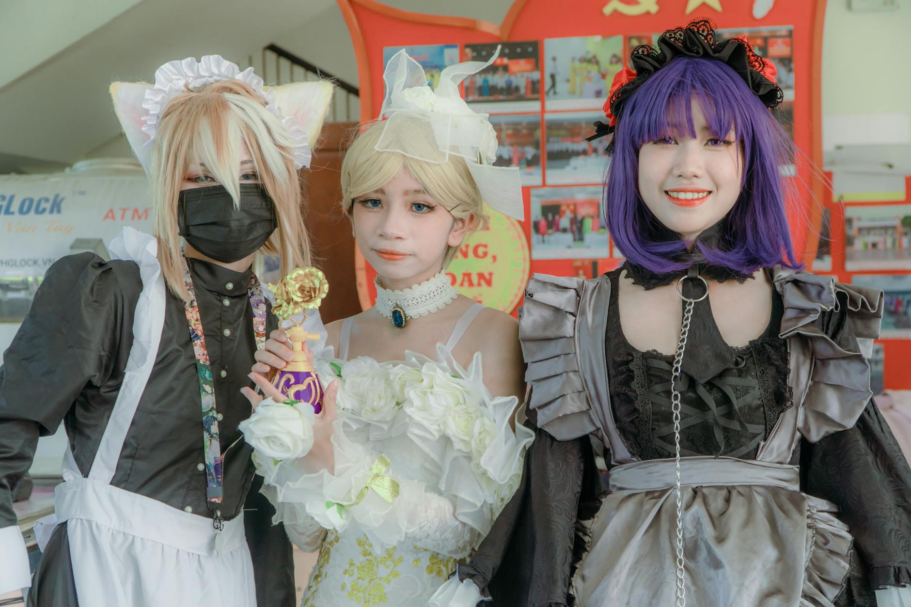 Three cosplayers in vibrant costumes and accessories pose for a photo, highlighting creativity and style.