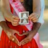 A joyful couple holding an ultrasound photo, celebrating pregnancy outdoors.