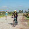 Cyclist and runner participating in outdoor rural race on dirt road.
