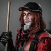A dramatic street performer in a striking red and black costume with makeup.