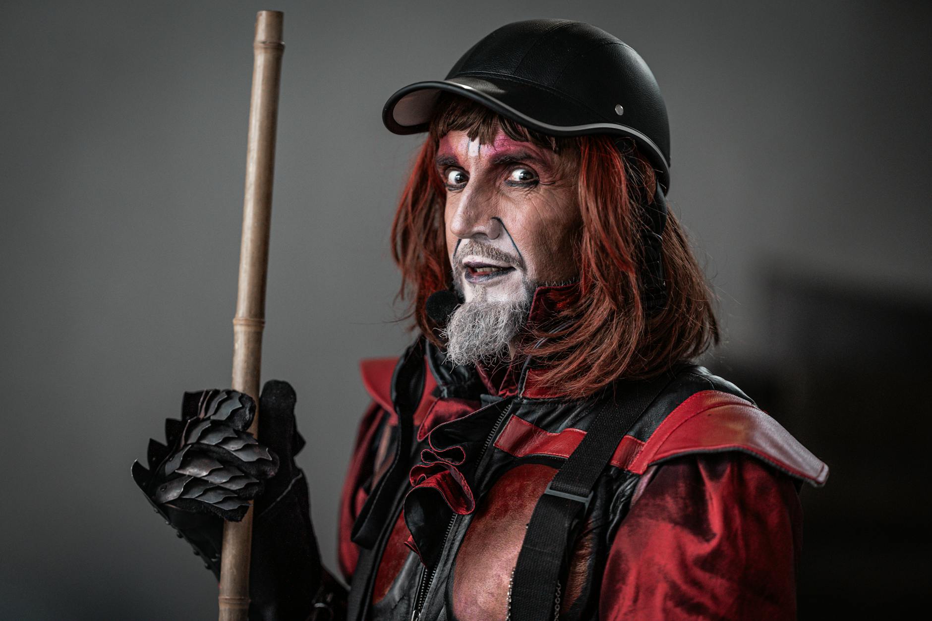 A dramatic street performer in a striking red and black costume with makeup.