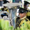Music band in ceremonial uniforms performing outdoors with brass instruments. Vibrant and festive atmosphere.