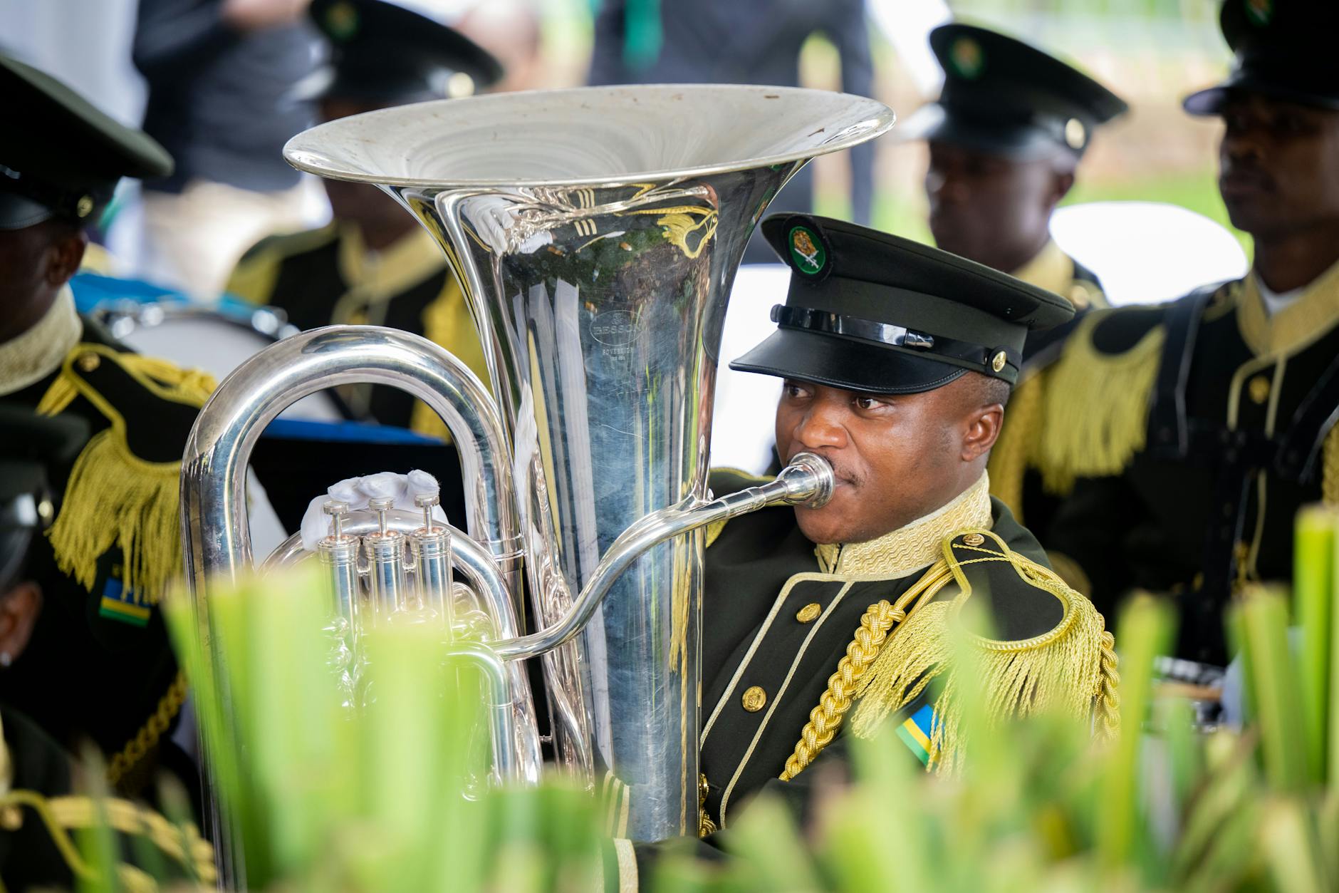 Music band in ceremonial uniforms performing outdoors with brass instruments. Vibrant and festive atmosphere.