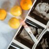 A pregnancy test surrounded by ultrasound scans and lemons on a white surface.