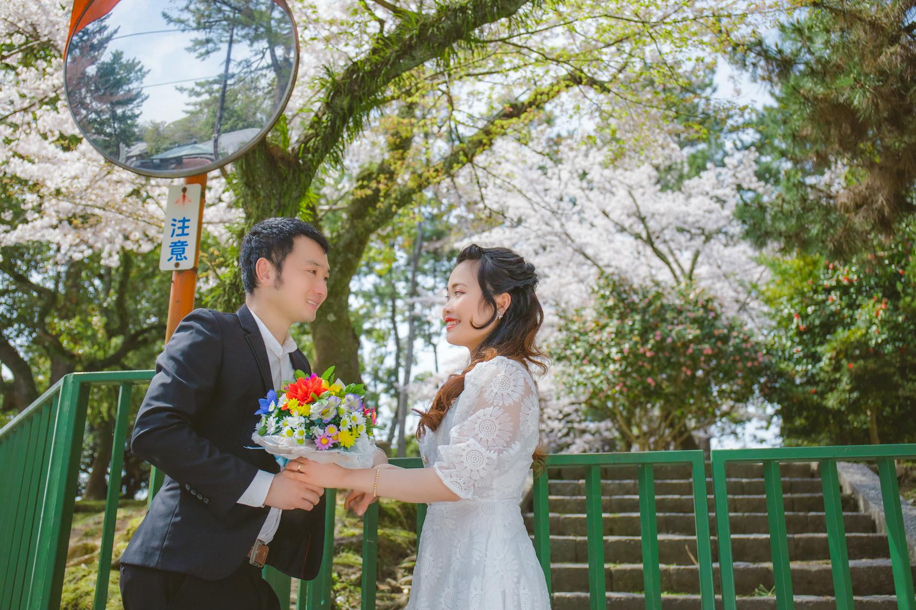 A happy couple sharing a moment under blooming cherry blossoms on a sunny spring day.