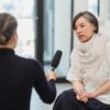 Professional interview setting with a female journalist and woman discussing indoors.