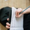 Detailed view of a hand composing music with pencil on sheet paper, creating a musical score.