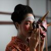 Captivating portrait of a geisha holding a Hannya mask, embodying Japanese culture and tradition.