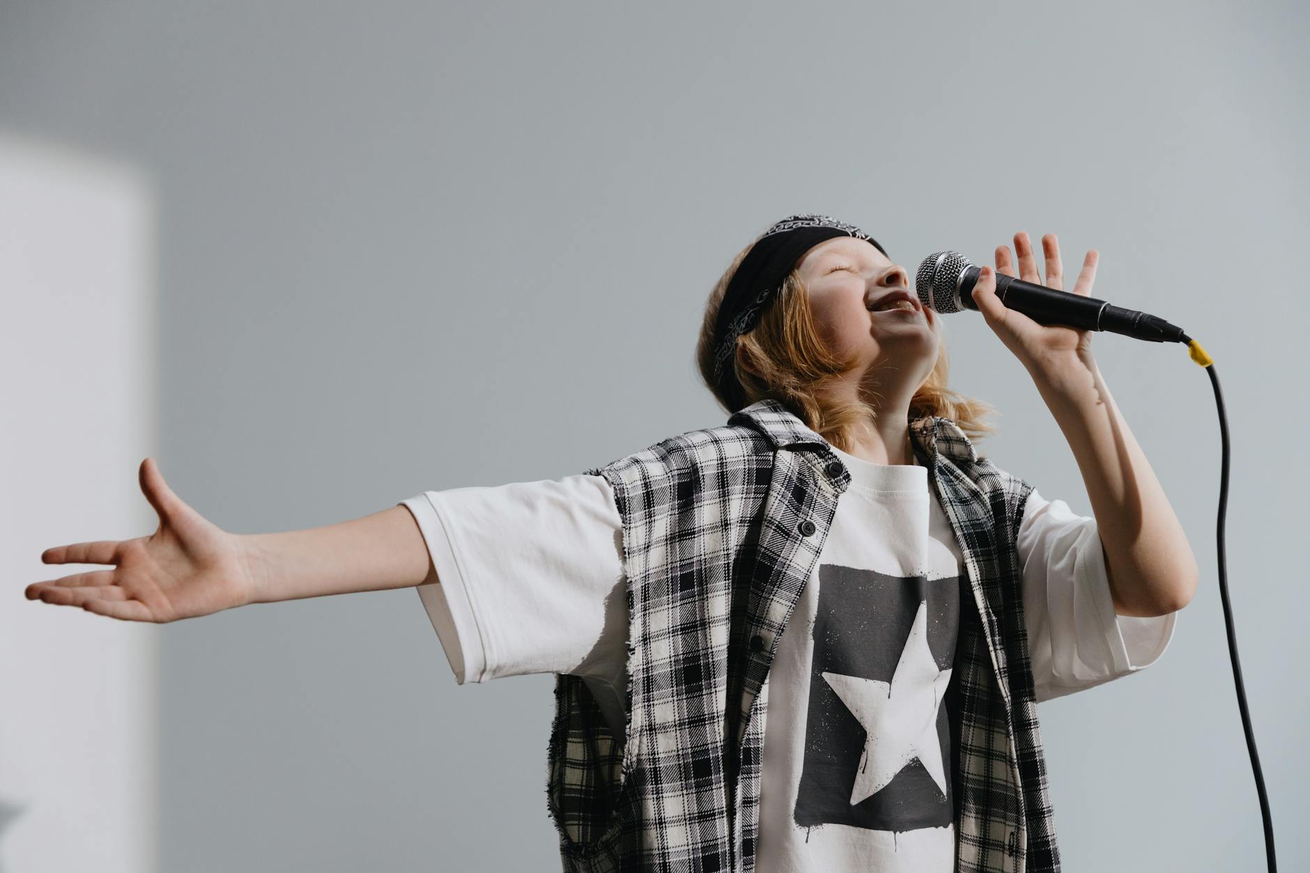 Energetic child singing on stage with microphone, expressing passion.