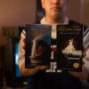 A person holding vintage VHS tapes in a cozy indoor setting.