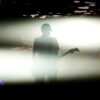 Silhouette of a guitarist performing under dramatic lighting, creating a striking stage presence.