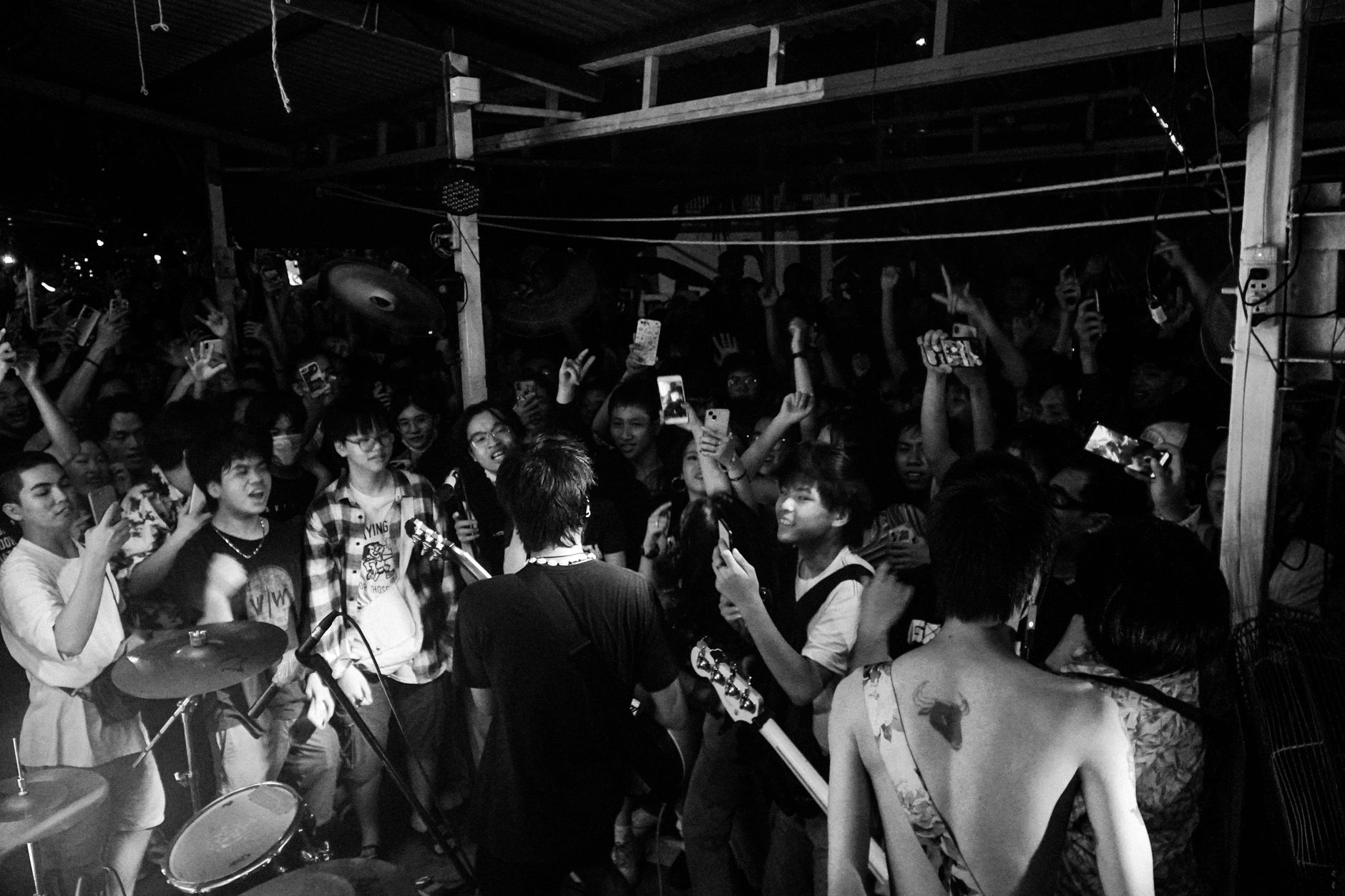 Black and white photo capturing a dynamic live band performing to an enthusiastic crowd.