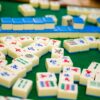 Close-up of colorful mahjong tiles on green felt, showcasing a variety of designs and symbols.