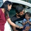 A joyful family moment with parents and child sitting in a car in Sanand, India.