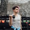 A young man lifting a dumbbell in an outdoor gym in Mexico City, promoting fitness and a healthy lifestyle.