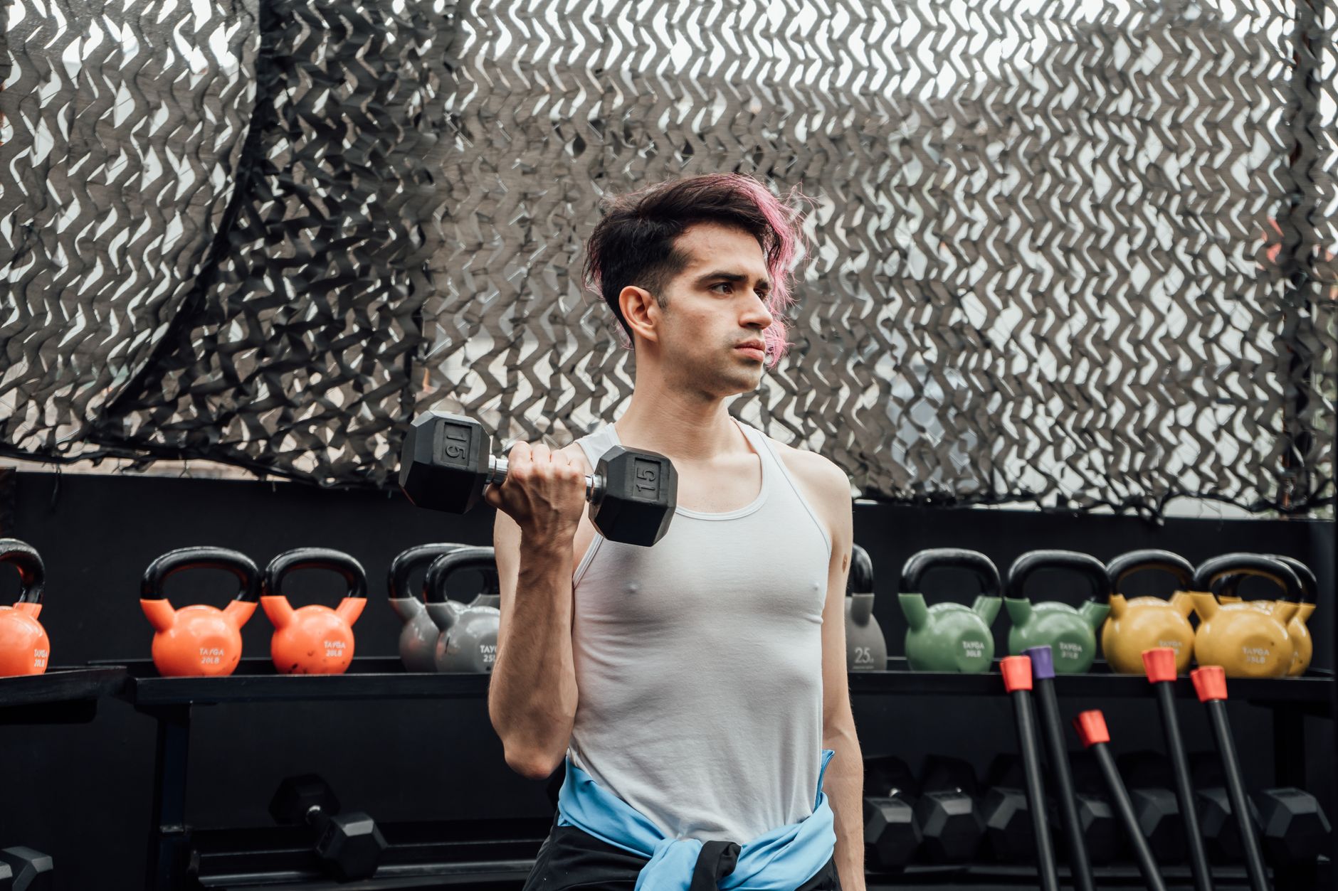 A young man lifting a dumbbell in an outdoor gym in Mexico City, promoting fitness and a healthy lifestyle.