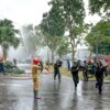 Firefighters and rescuers in action controlling a fire outdoors, using hoses.