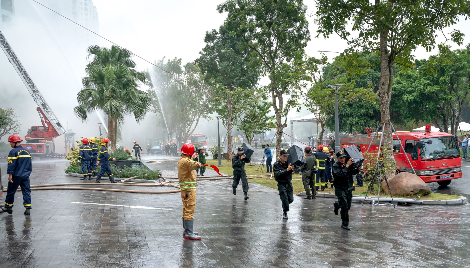 Firefighters and rescuers in action controlling a fire outdoors, using hoses.