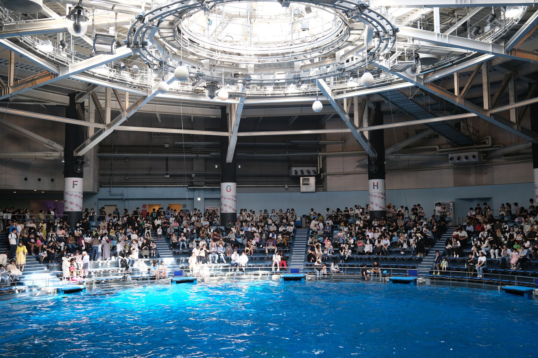 A vibrant indoor aqua park with blue water and a lively crowd in Shinagawa, Tokyo.