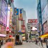 A bustling street in Akihabara, Tokyo filled with bright neon signs and pedestrians.