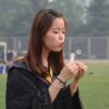 Young graduate celebrates outdoors, making a wish with a dandelion.