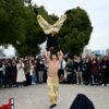 Acrobatic performers captivating an outdoor audience with skillful stunts in a lively street show.