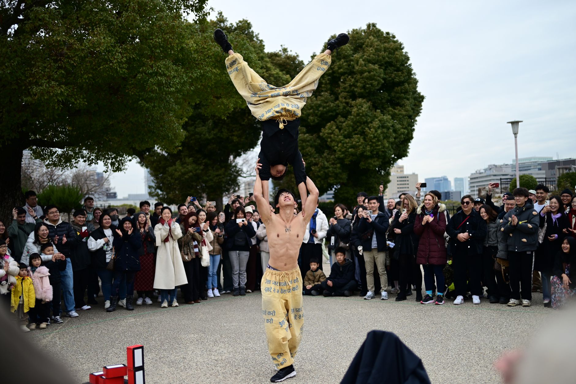 Acrobatic performers captivating an outdoor audience with skillful stunts in a lively street show.