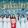 Group of graduates posing joyfully in front of colorful graduation mural.