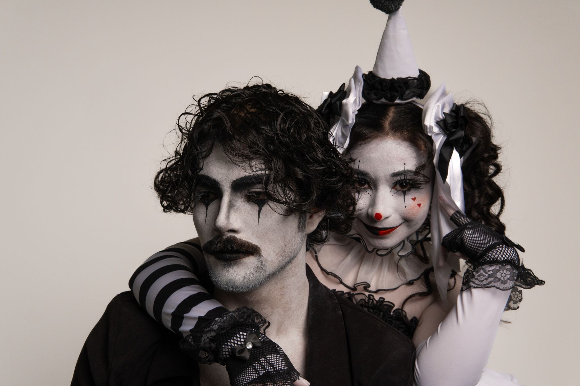 Two adults in harlequin costume and mime makeup, capturing a classic theatrical scene
