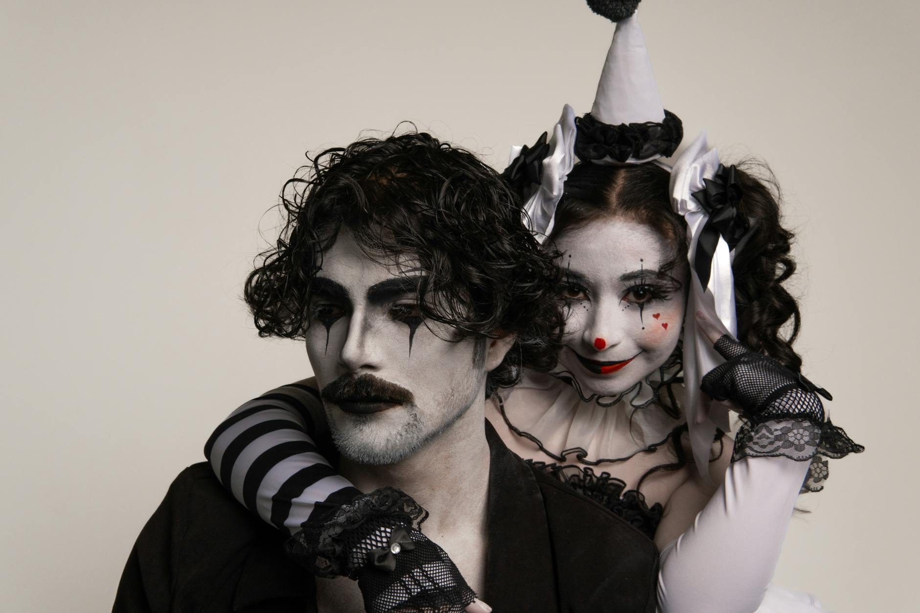 Two adults in harlequin costume and mime makeup, capturing a classic theatrical scene