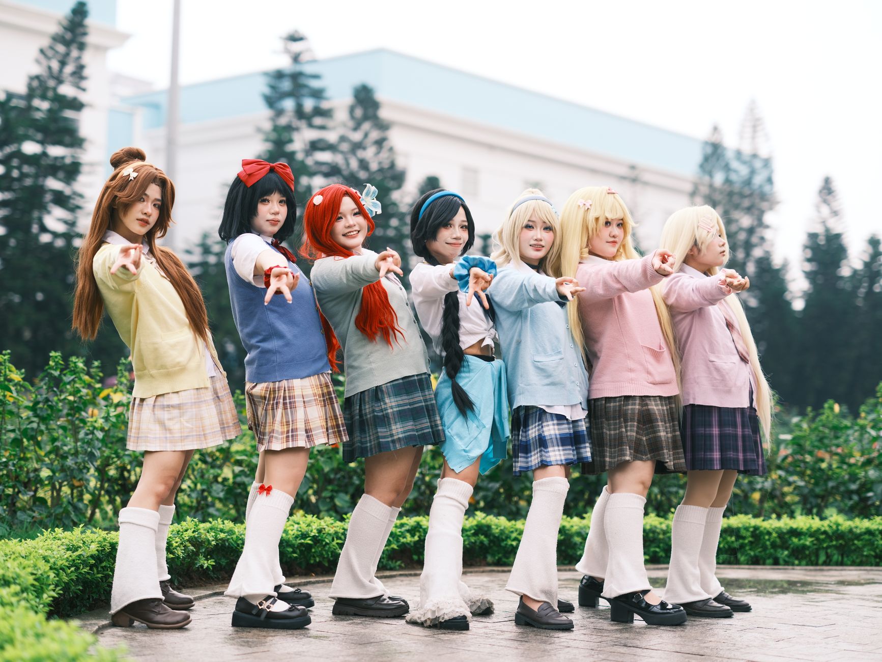 A vibrant group of cosplayers posing outdoors in anime-inspired costumes, showcasing colorful outfits and playful poses.