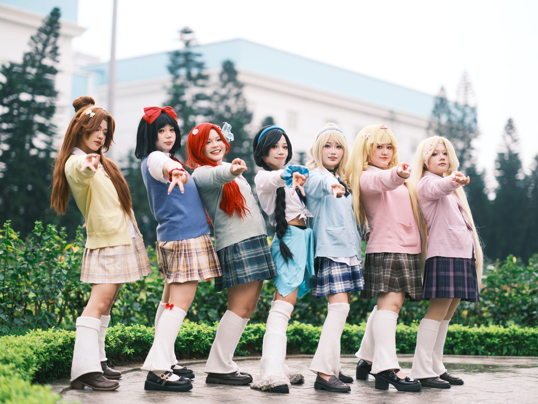 A group of six people in anime-themed cosplay posing outdoors. Energetic and colorful.