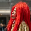 A Japanese performer in vibrant red wig captures attention during a street event in Tokyo.