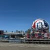 View of Vancouver's Science World featuring FIFA display and BC Place Stadium under a clear blue sky.