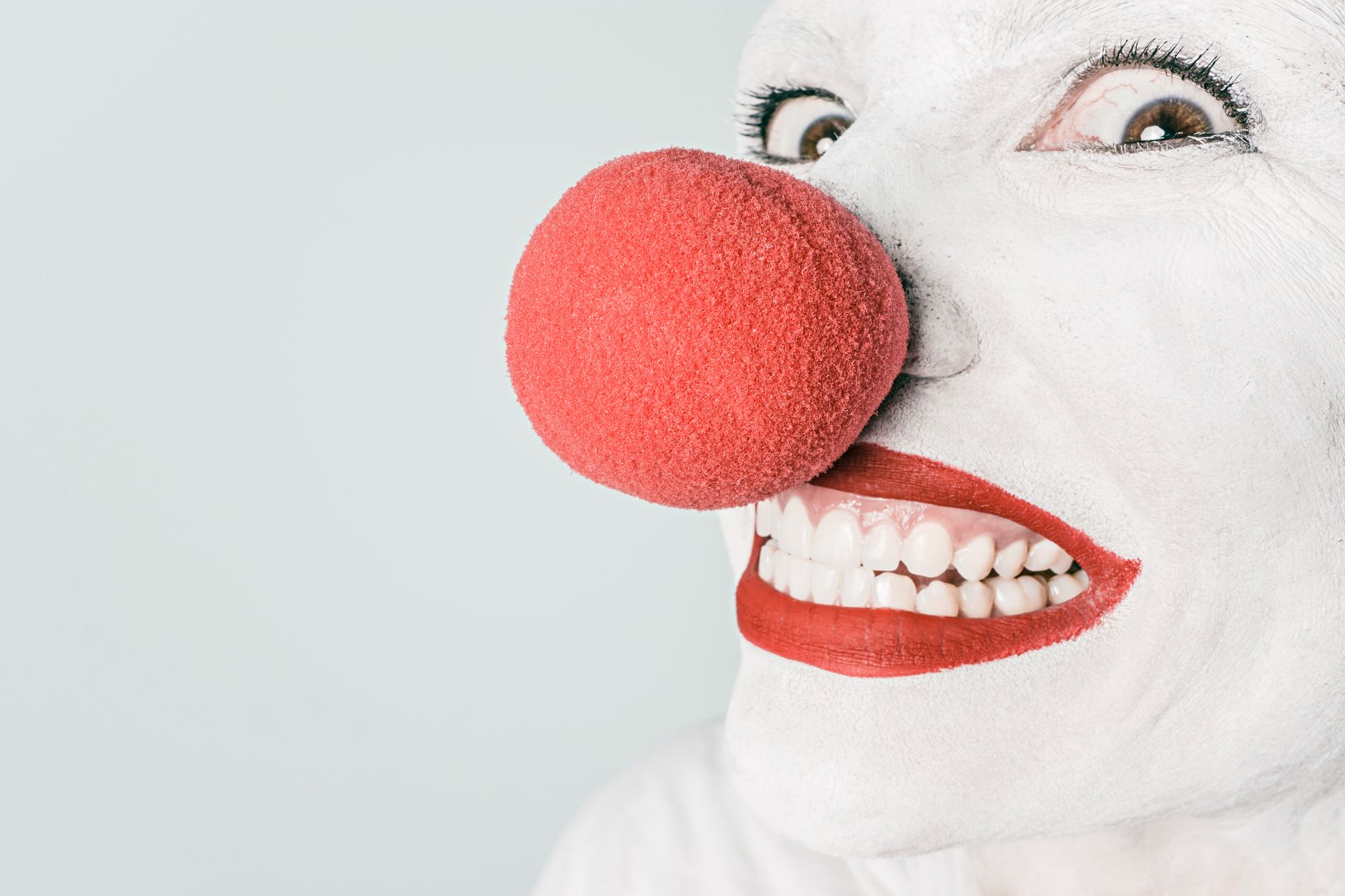 Bright close-up of a clown's face with red nose and makeup, showcasing humor and joy.