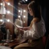 A woman in a dressing room reading a script, surrounded by makeup and lights.