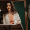 Professional female musician recording a song in a studio setting with microphone.