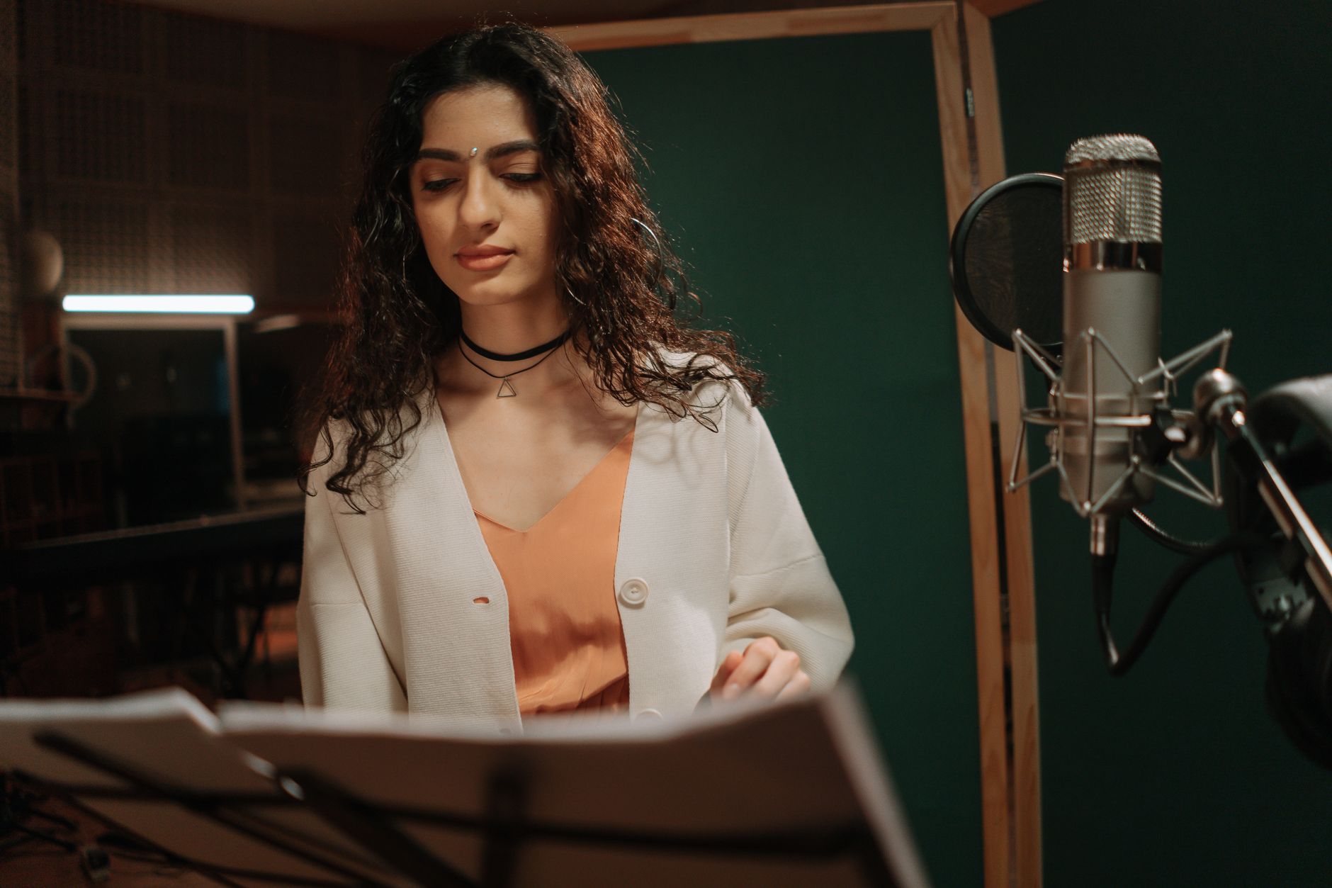 Professional female musician recording a song in a studio setting with microphone.