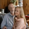 Heartwarming scene of a grandfather with his granddaughter indoors, sharing smiles and joy.