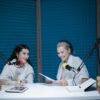 Two women recording a podcast in a soundproof studio with professional equipment.
