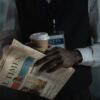 Close-up of a journalist holding a newspaper and coffee cup, conveying press and media concept.