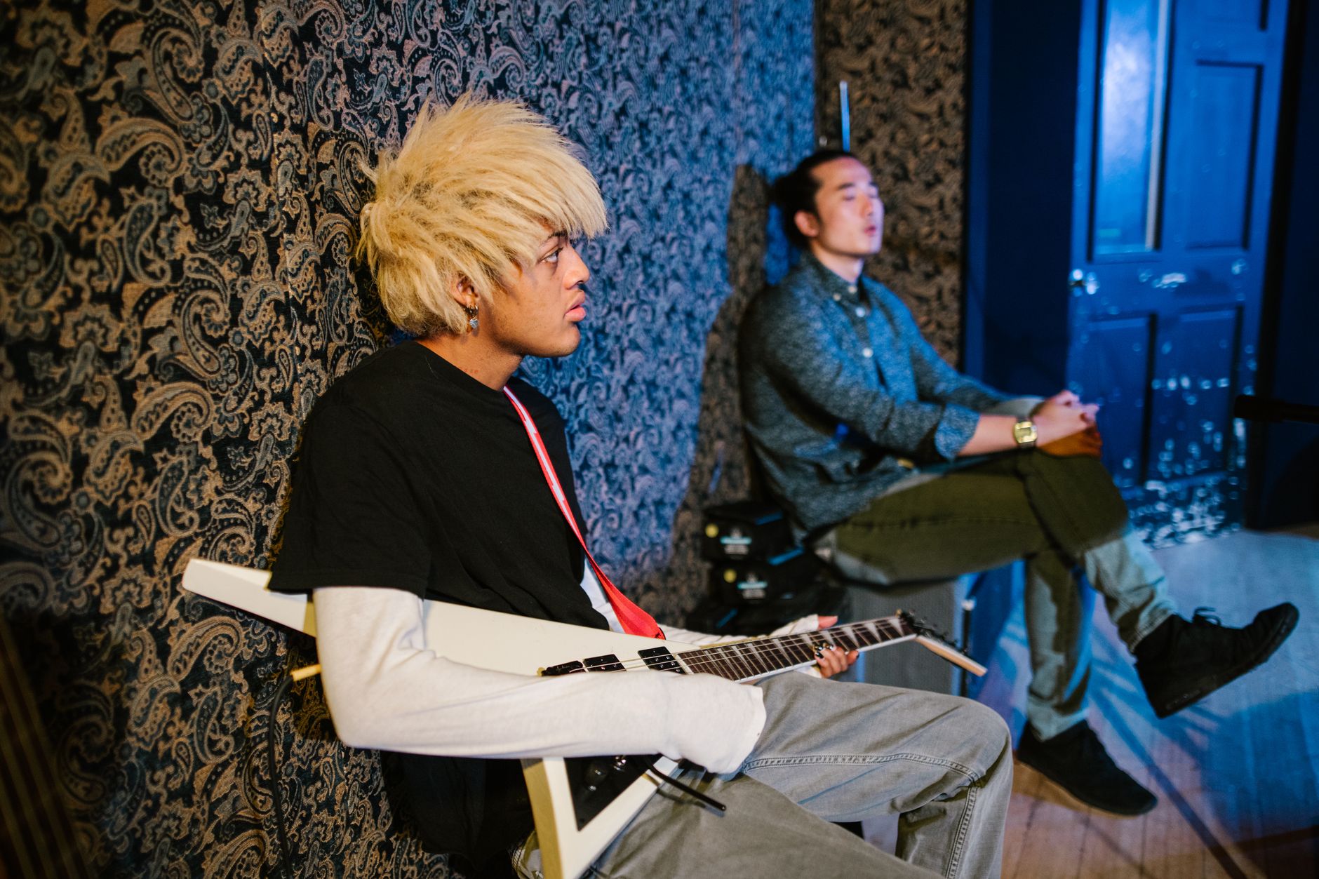Two young musicians in a studio, featuring an electric guitar and artistic vibe.