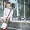 A young man sitting on a street, playing a shamisen, reflecting modern urban culture.