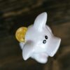 Close-up of a bitcoin coin inserted in a white piggy bank, symbolizing cryptocurrency savings.