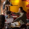 Diverse film crew with clapperboard in café setting filming scene.