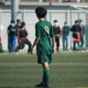 Youth soccer player in green jersey on football field during match.