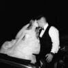 Romantic newlyweds kissing under the night sky in a classic car.