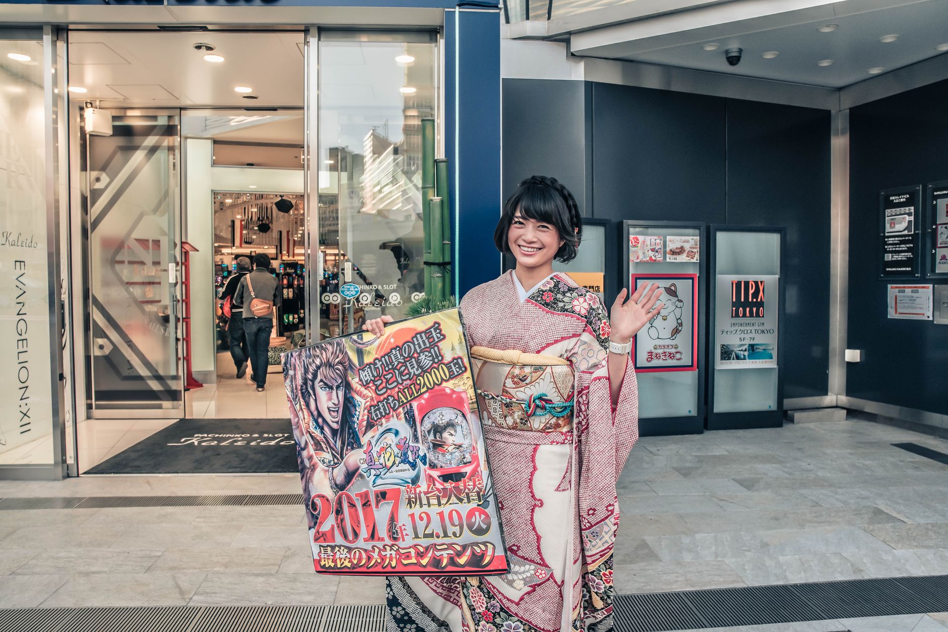 Asian woman in kimono holding promotional sign outside a store.